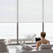Luxury smart shades in a bright oceanfront home controlled by tablet with automated window treatment integration by Sound & Vision Technology