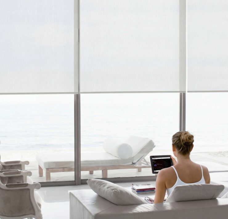 Luxury smart shades in a bright oceanfront home controlled by tablet with automated window treatment integration by Sound & Vision Technology