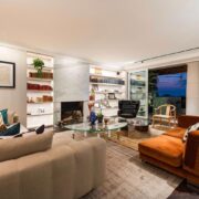 Trazzo luxury living room lighting design with fireplace lighting, illuminated shelving, recessed lighting, and warm indoor-outdoor ambiance.