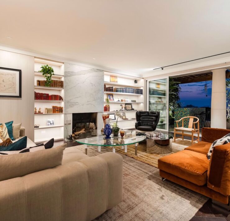 Trazzo luxury living room lighting design with fireplace lighting, illuminated shelving, recessed lighting, and warm indoor-outdoor ambiance.