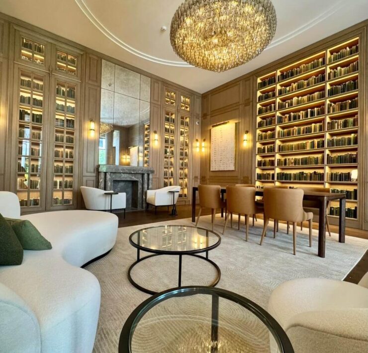 Trazzo luxury library lighting design with illuminated bookshelves, chandelier, wall sconces, fireplace, and warm architectural lighting.