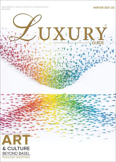 Luxury Guide Cover Winter 21_22 Luxury Guide Winter 2021–22 cover featuring a colorful contemporary art installation composed of suspended figures above a mirrored reflection.